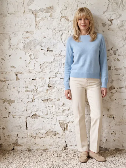 Frau in helblauem Alpaka Pullover und Hose in beige