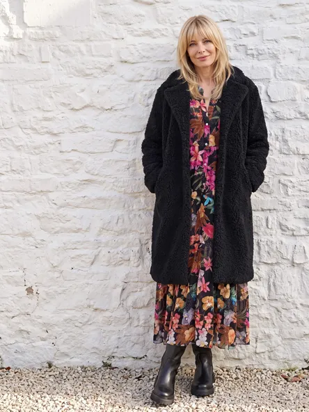 Frau in floralem Kleid und schwarzem Mantel