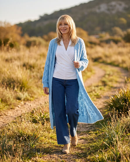 Frau in hellblauem Strickmantel und Jeans