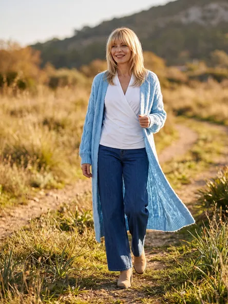 Frau in hellblauem Strickmantel und Jeans